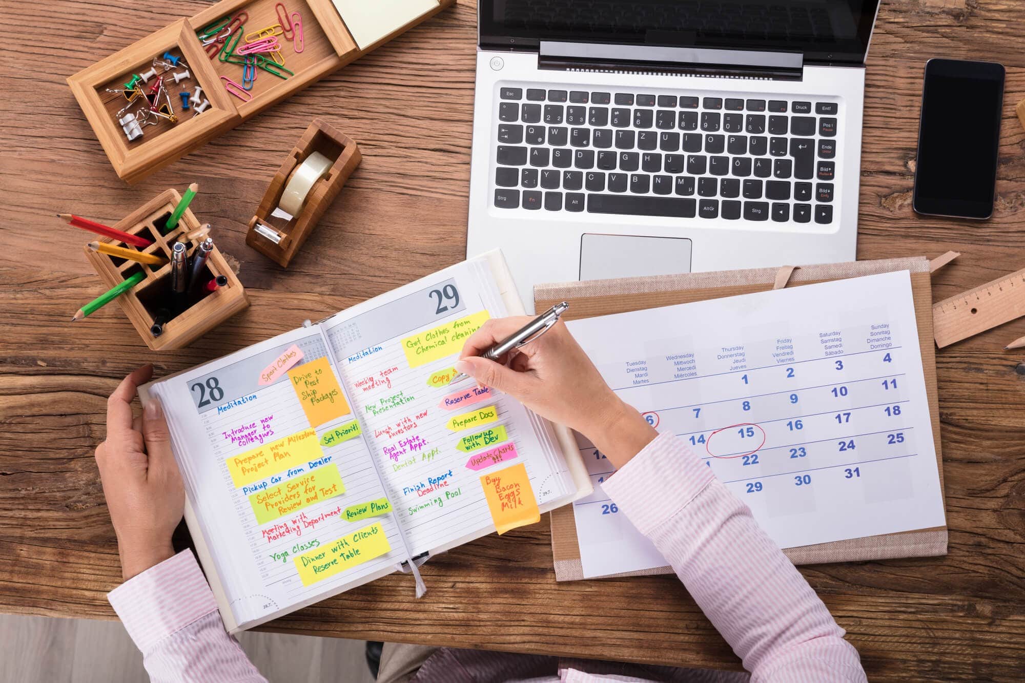 Close-up Of Businesswoman Writing Schedule In Calendar